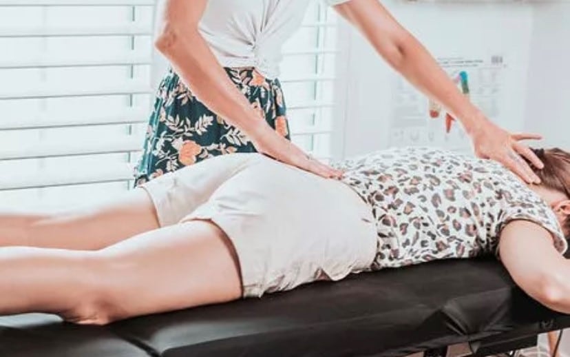 A practitioner performing the Spinal Flow Technique on a client, emphasizing gentle touch to stimulate innate healing.